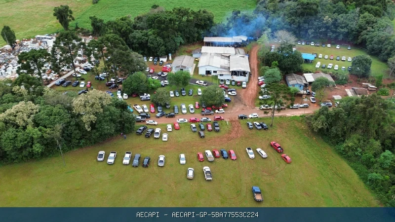 Fotografia aérea colorida mostrando a igreja, árvores, áreas de estacionamento e grande concentração de veículos e pessoas em uma festa na Comunidade Cantú Santa Rita. 
O evento aconteceu no domingo 13/09/2026. Costelada tradicional.
